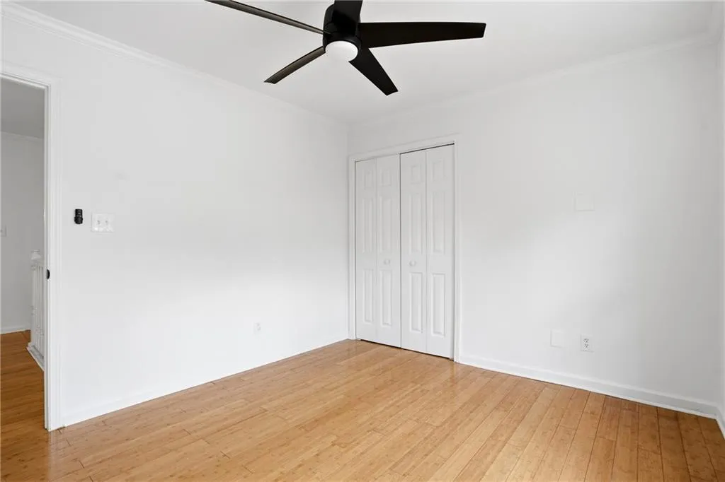 Unfurnished bedroom with ornamental molding, a closet, light wood finished floors, and a ceiling fan