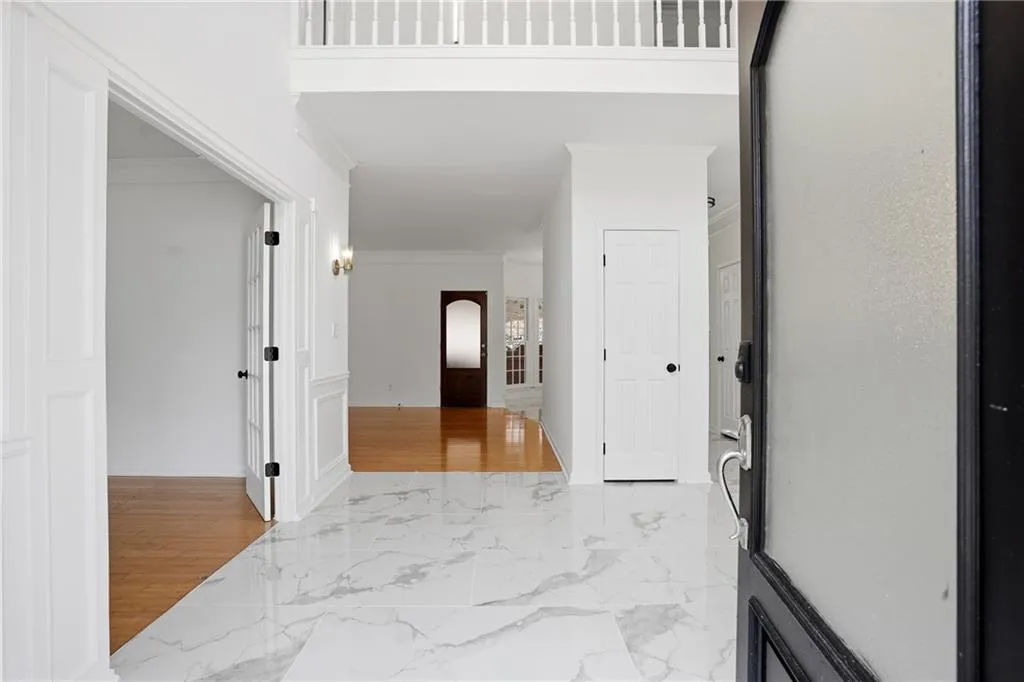 Corridor featuring crown molding and light marble finish floors