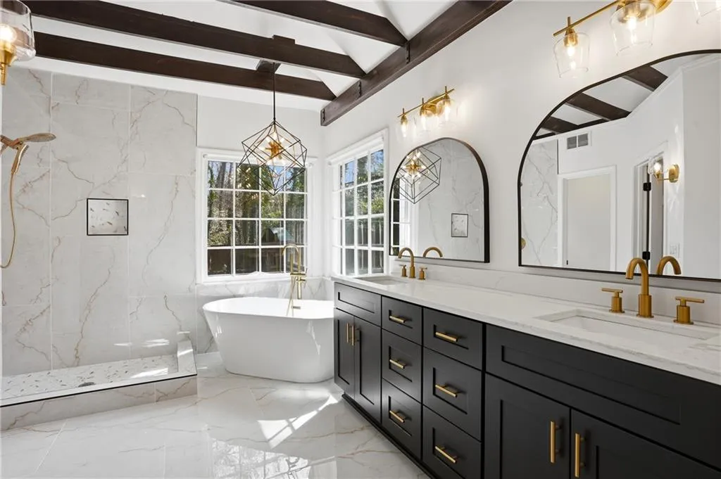 Bathroom with double vanity, a marble finish shower, a freestanding bath, beam ceiling, and light marble finish floors