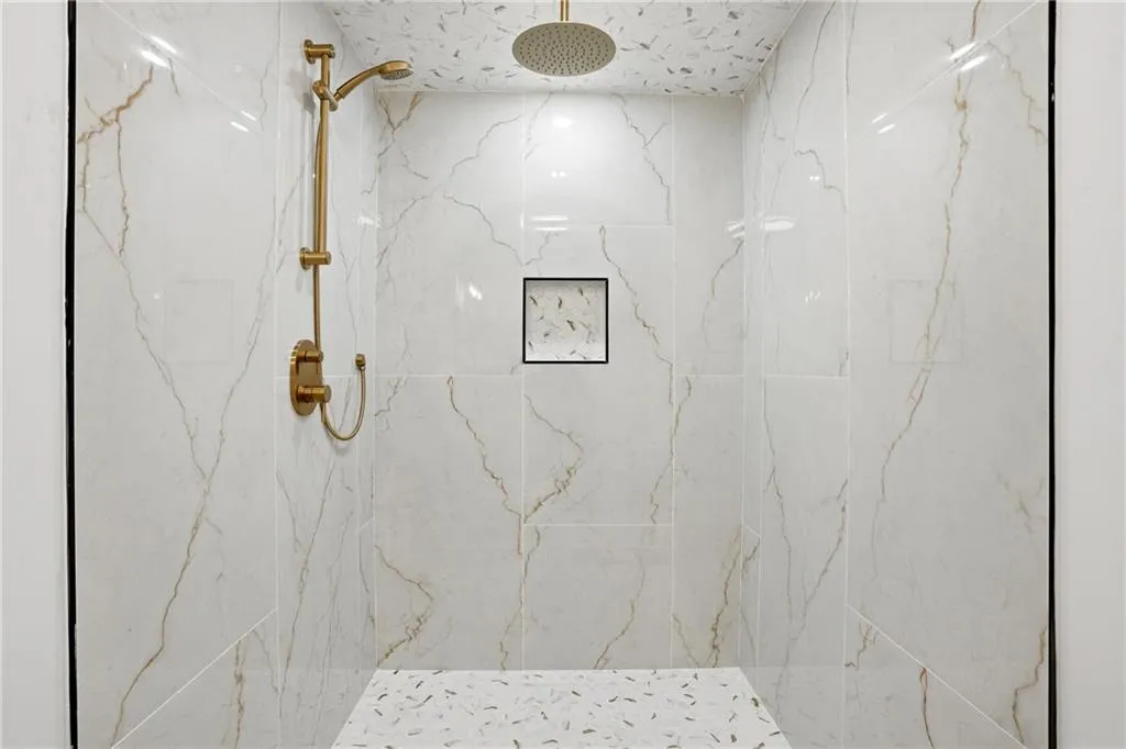 Full bath with a marble finish shower