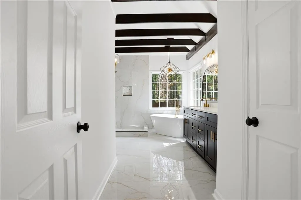 Full bathroom featuring light marble finish floors, a marble finish shower, beam ceiling, vanity, and a freestanding bath