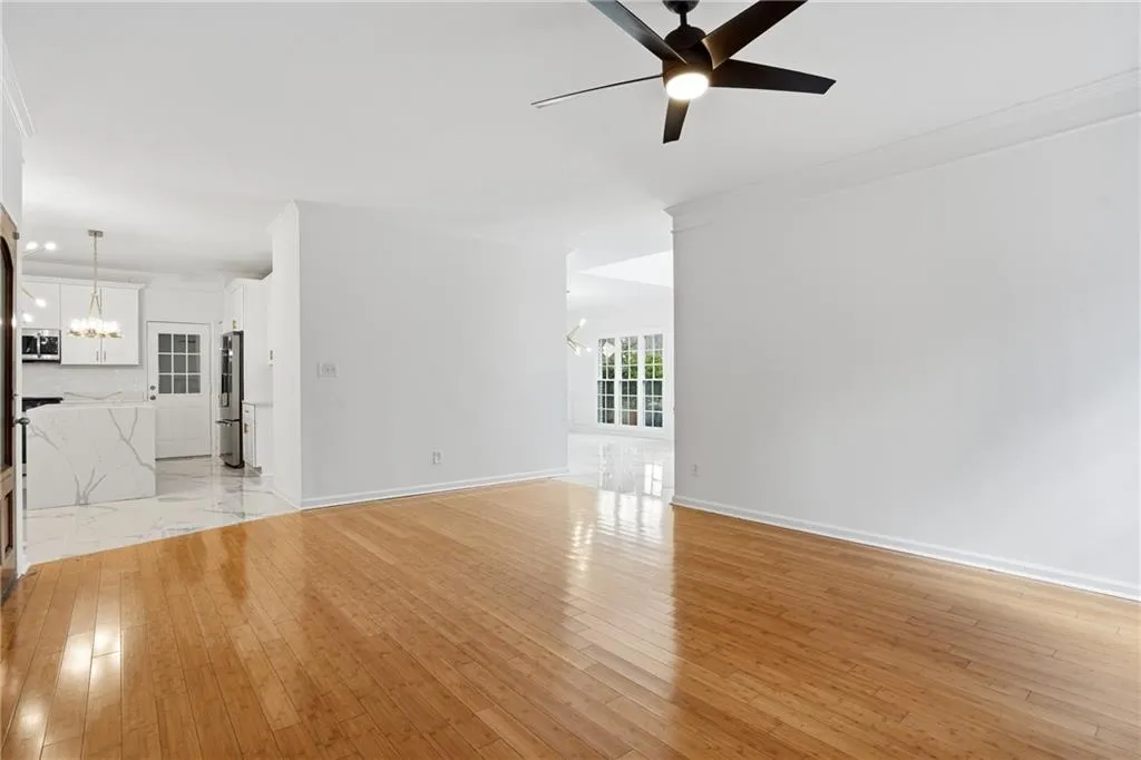 Unfurnished living room with hanging lights, ornamental molding, a ceiling fan, and light wood-style floors