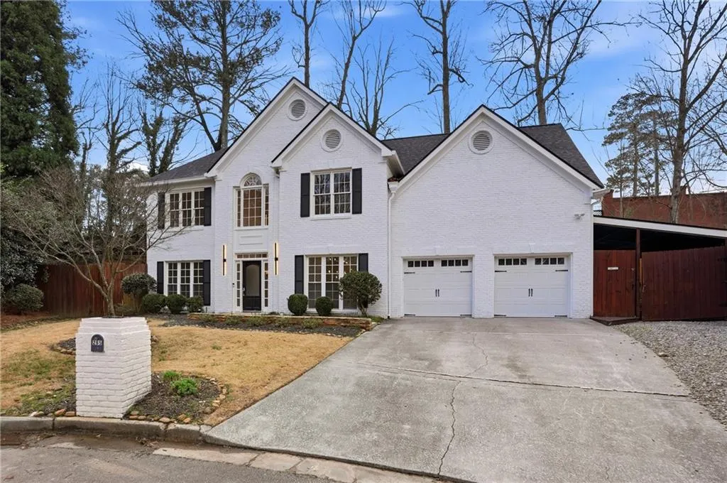 View of front of home with brick siding, a garage, and driveway