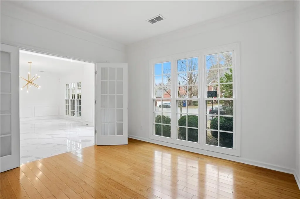 Empty room featuring hanging lights, crown molding, and light wood-style flooring