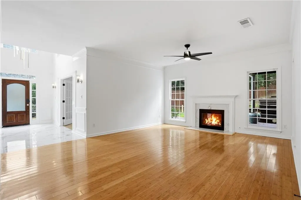 Unfurnished living room with a high end fireplace, ceiling fan, light wood-style flooring, and ornamental molding