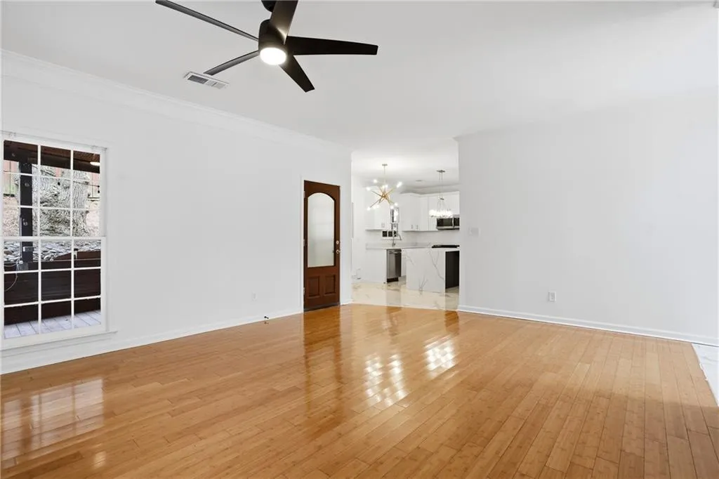 Unfurnished living room featuring suspended lighting, a ceiling fan, light wood finished floors, and ornamental molding