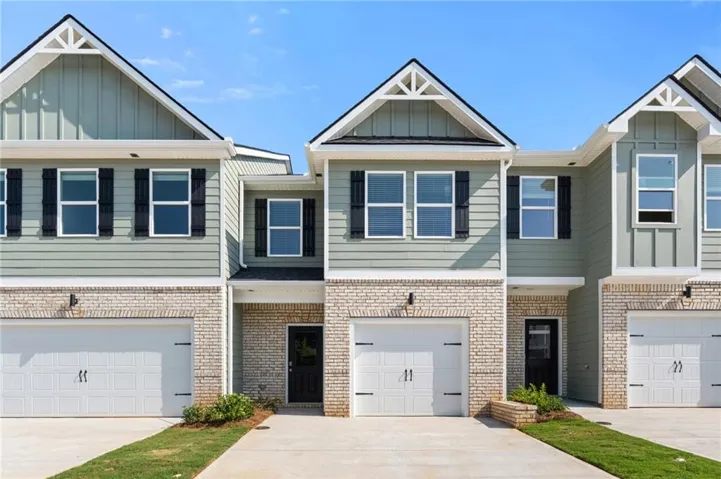 Modern townhouse exterior featuring brick and horizontal siding, an attached garage, and a covered entry