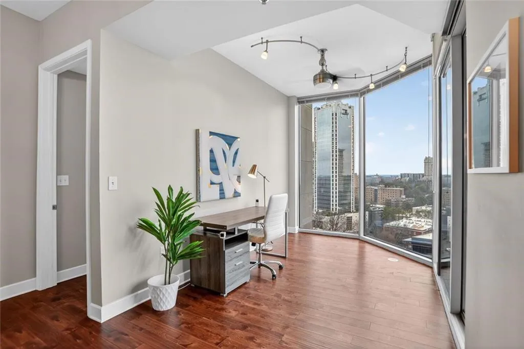 Office featuring dark wood-type flooring, floor to ceiling windows, a city view, and rail lighting