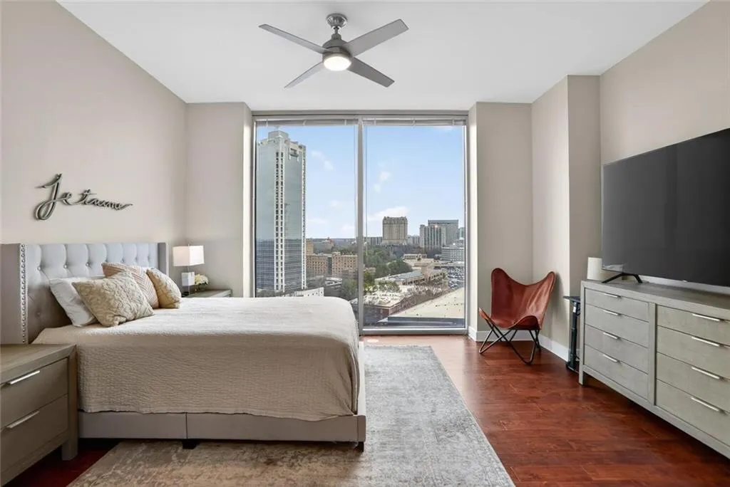 Bedroom with floor to ceiling windows, dark wood-style flooring, a ceiling fan, and access to exterior