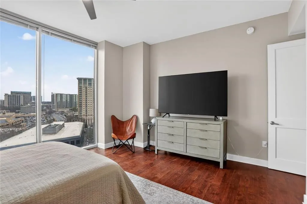Bedroom with expansive windows, dark wood-type flooring, ceiling fan, and access to outside