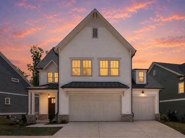 Modern farmhouse exterior featuring white board-and-batten siding, a prominent gable, a covered entry porch, a two-car garage, and a single-car garage