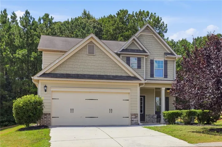 Two-story residence featuring a two-car garage, brick accents, and a covered entry