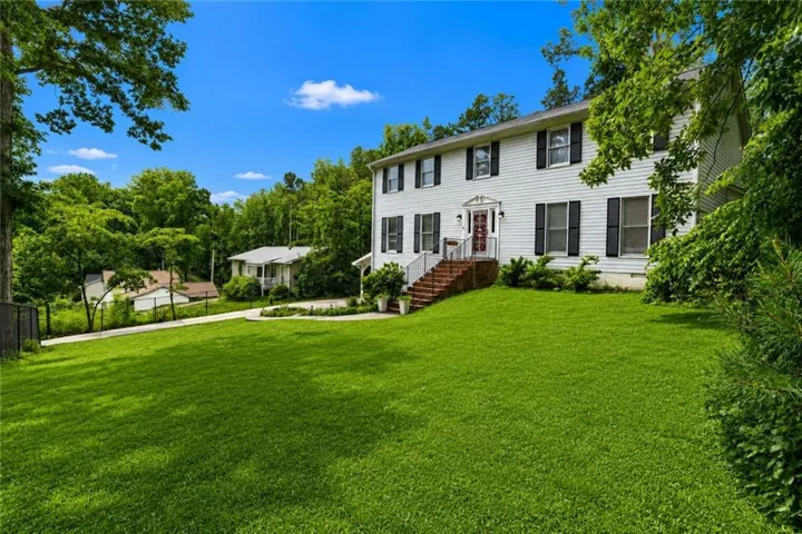 White exterior residence featuring black louvered shutters and a columned entryway