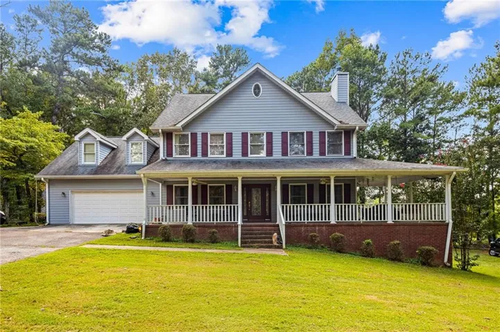 Two-story residence featuring light blue siding, a covered front porch with white railings, and a two-car garage with dormer windows