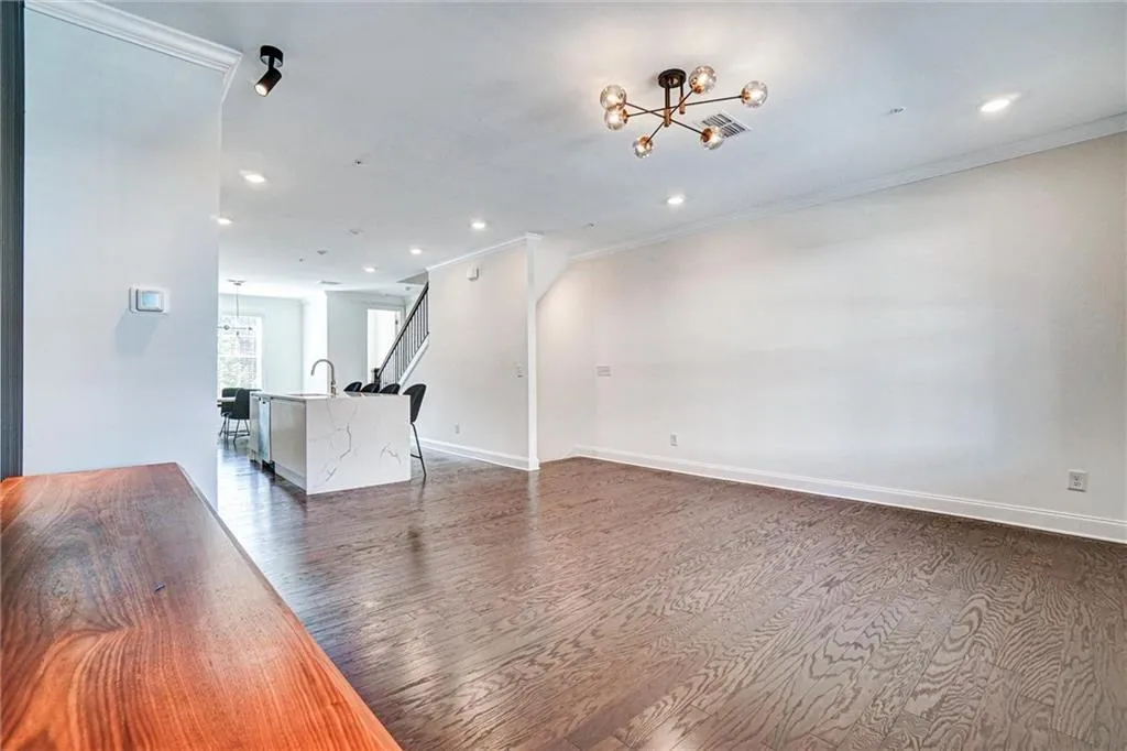 Unfurnished living room featuring a chandelier, dark wood-style floors, recessed lighting, and crown molding