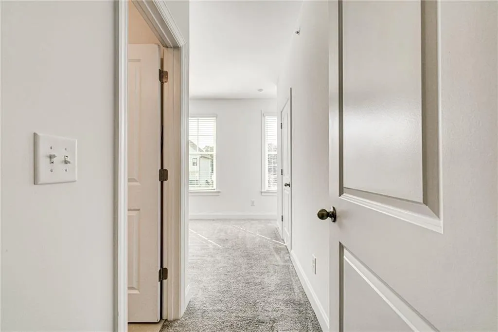 Hall featuring light colored carpet and baseboards