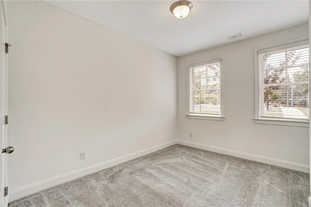 Empty room with light colored carpet and baseboards
