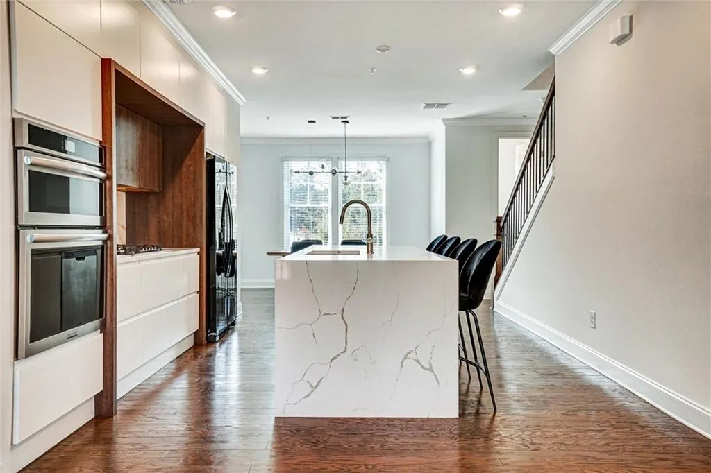 Kitchen featuring ornamental molding, dark wood-style flooring, decorative light fixtures, a breakfast bar, and modern cabinets