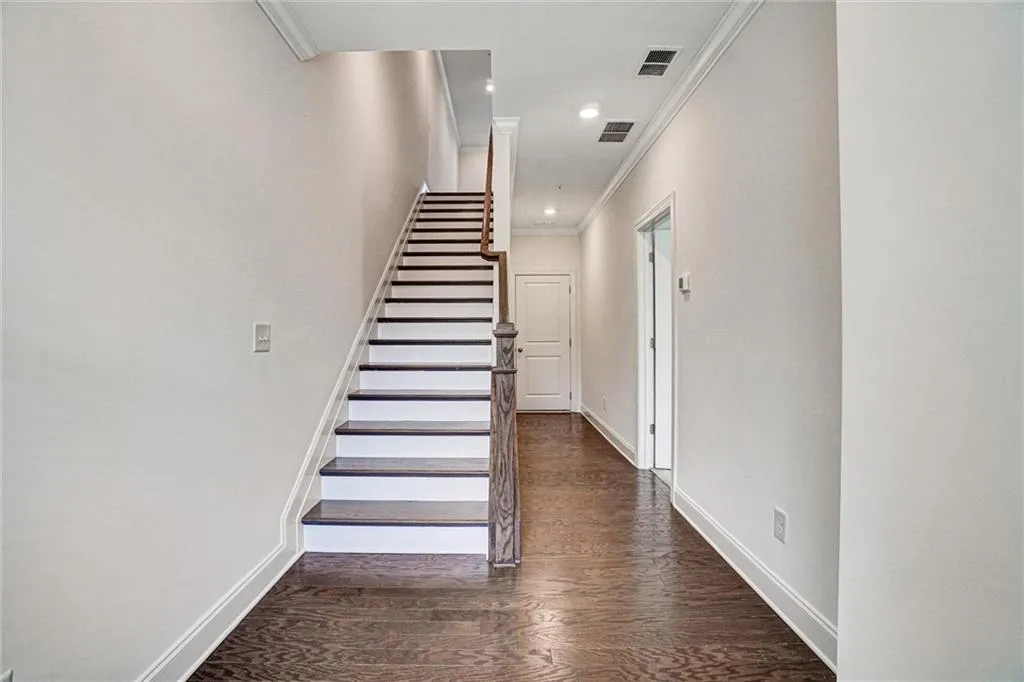 Stairs with ornamental molding, wood finished floors, and recessed lighting