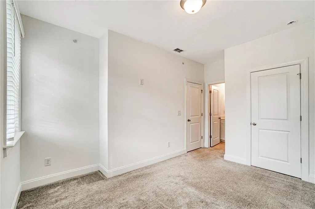 Unfurnished bedroom featuring light colored carpet and ensuite bath