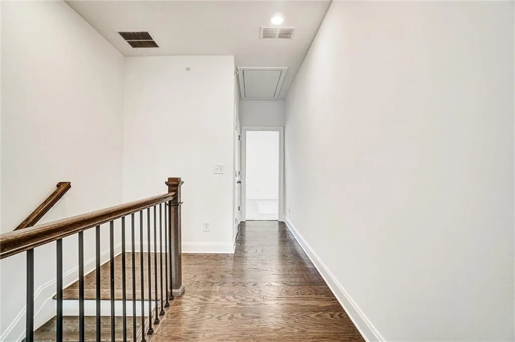 Hall with dark wood-type flooring, an upstairs landing, attic access, and recessed lighting