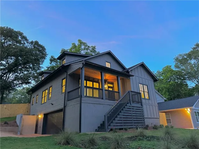 Modern farmhouse exterior with dark gray siding, covered porch, and exterior lighting