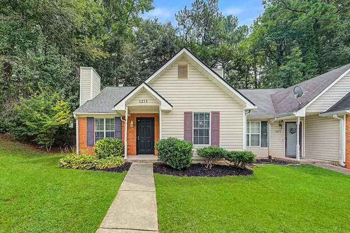 Cream siding exterior with brick accents, dark shutters, and a prominent front door