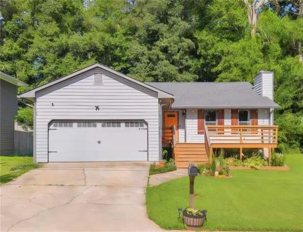 Light gray siding exterior with a front-facing attached garage, a raised wood deck, and a vibrant orange entry door