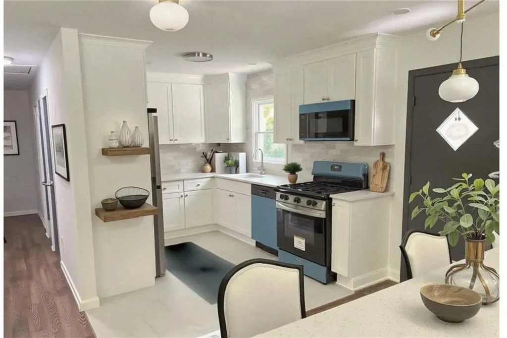 Kitchen with appliances with stainless steel finishes, white cabinets, decorative light fixtures, tasteful backsplash, and light wood-type flooring