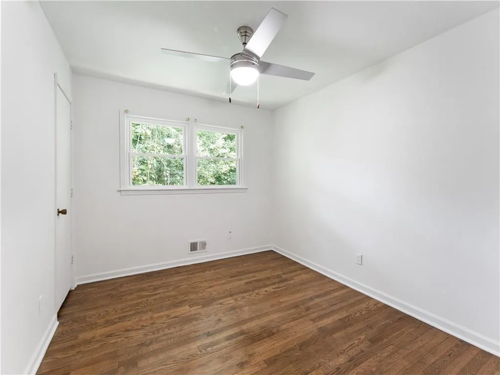 Spare room with dark wood finished floors and a ceiling fan