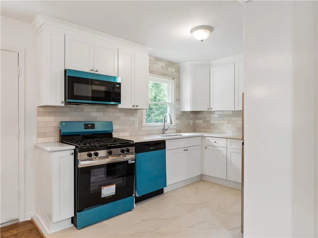 Kitchen featuring stainless steel range with gas cooktop, white cabinets, tasteful backsplash, dishwasher, and light stone countertops