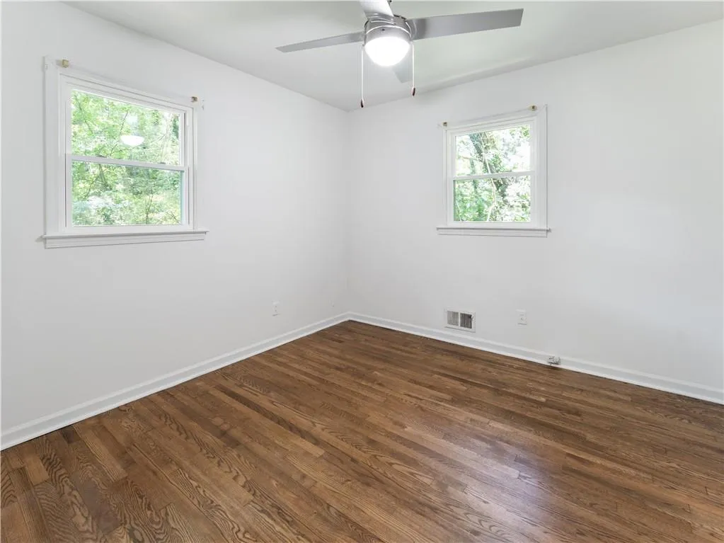 Empty room featuring dark wood-style floors and a ceiling fan