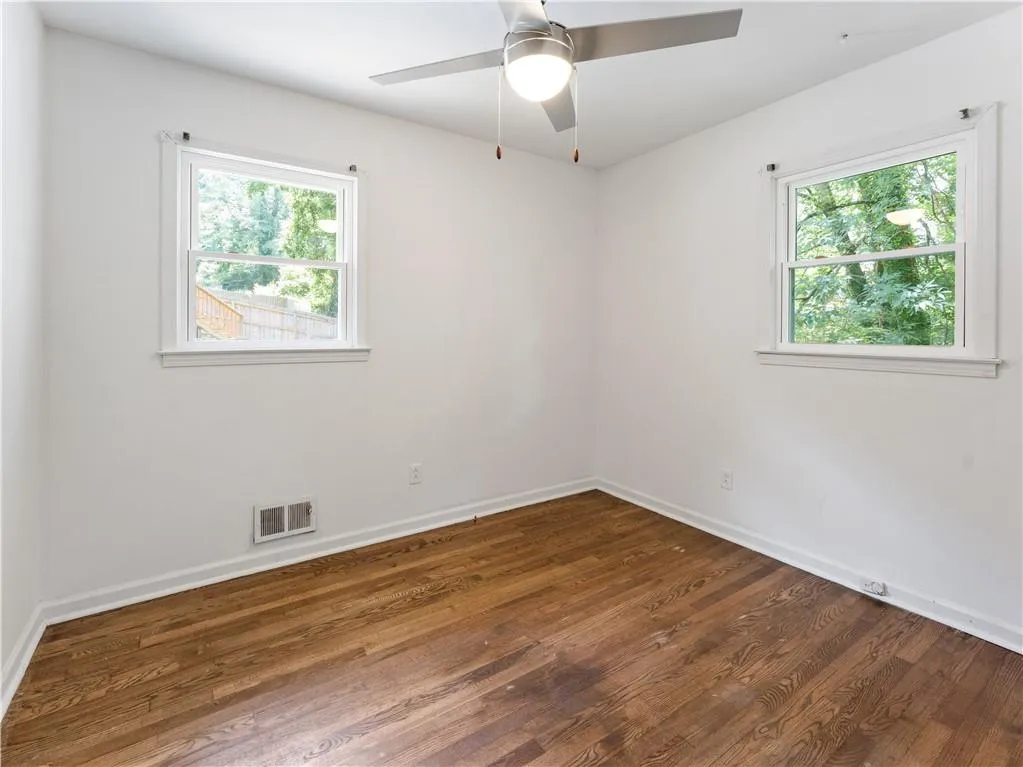 Unfurnished room with dark wood-style floors and a ceiling fan