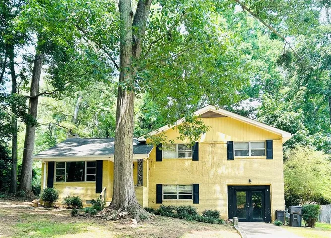 Yellow brick exterior with black shutters and a prominent tree in the foreground