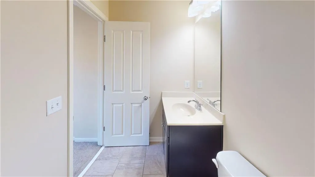 Secondary Bathroom with toilet, vanity, and tile patterned flooring