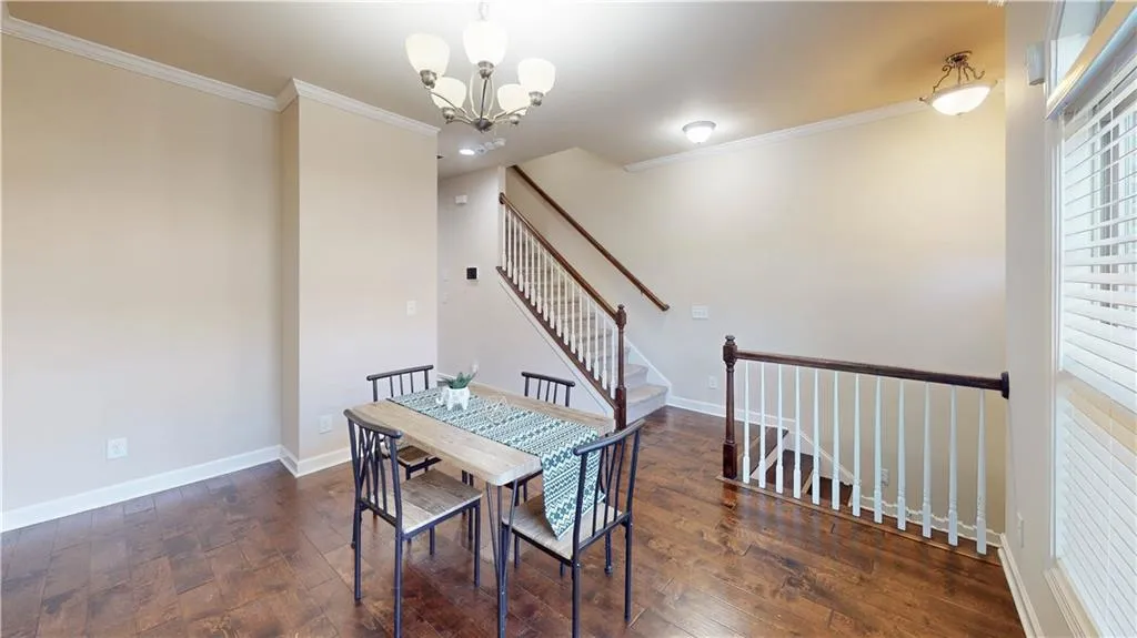 Dining area with dark wood-type flooring, a notable chandelier, and ornamental molding