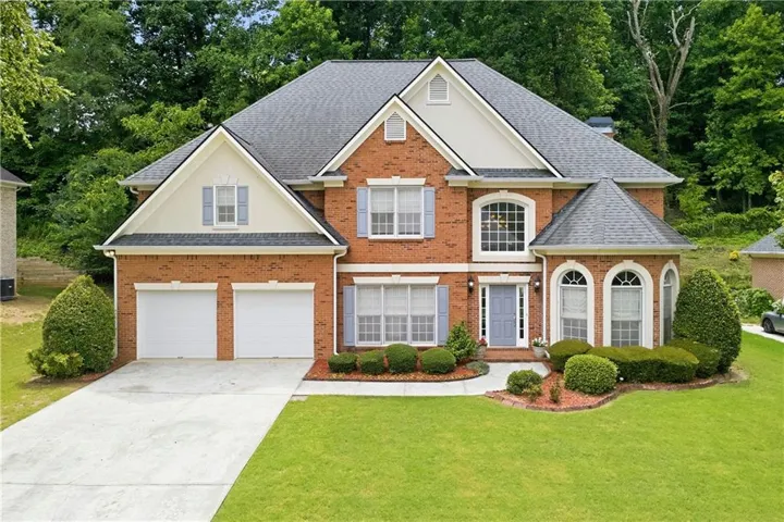 Brick exterior with light-colored trim and a dark shingle roof