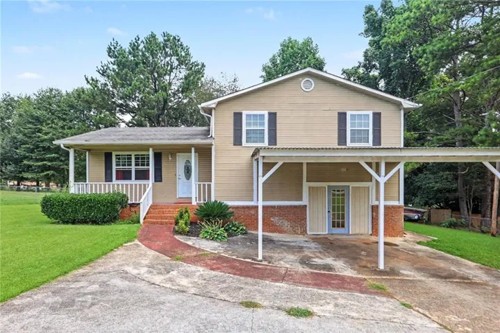 Exterior featuring siding construction, a covered front porch, a carport, a gabled roof, and a concrete driveway