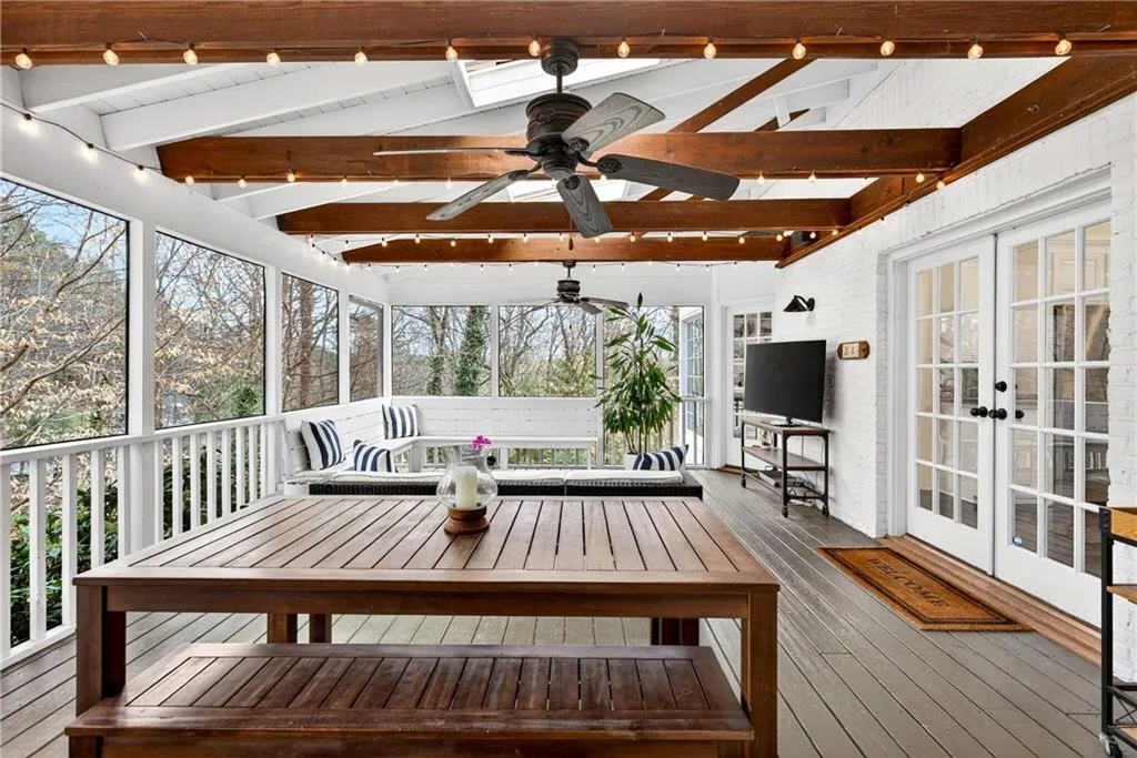 Sunroom / solarium featuring french doors, a wooden deck, ceiling fan, and lofted ceiling with beams