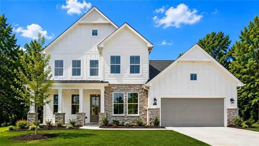 Modern farmhouse exterior with white board and batten siding, stone facade, and a covered porch with column supports
