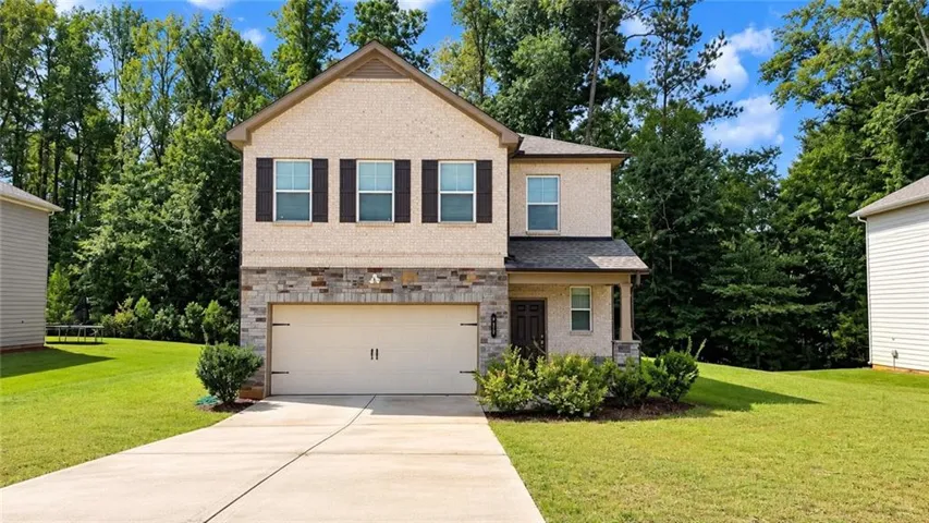 Two-story residence featuring a two-car garage, stone facade accents, and a covered entry
