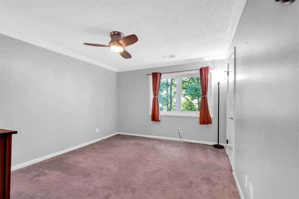 Carpeted spare room featuring crown molding, a textured ceiling, and ceiling fan