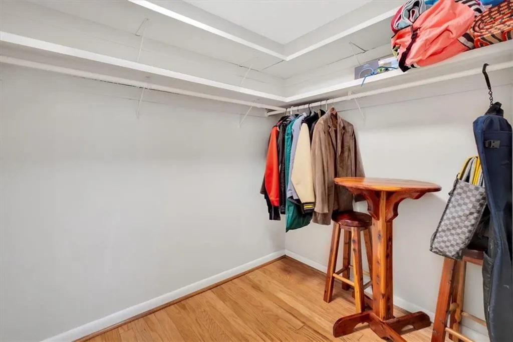 Walk in closet with hardwood / wood-style flooring