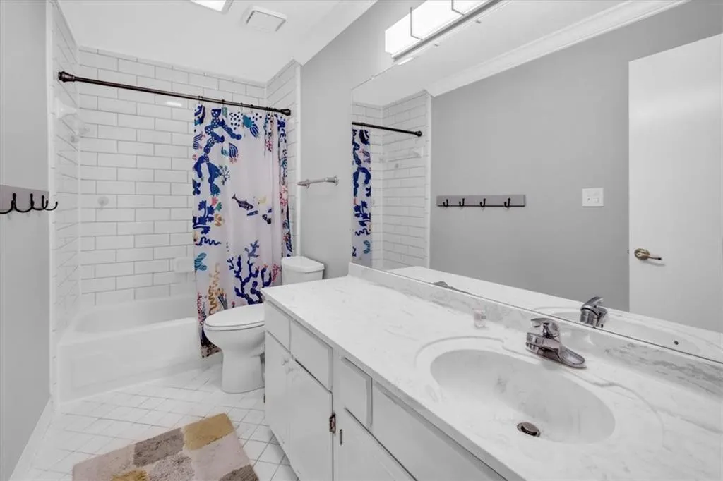 Full bathroom with tile flooring, oversized vanity, toilet, and shower / tub combo