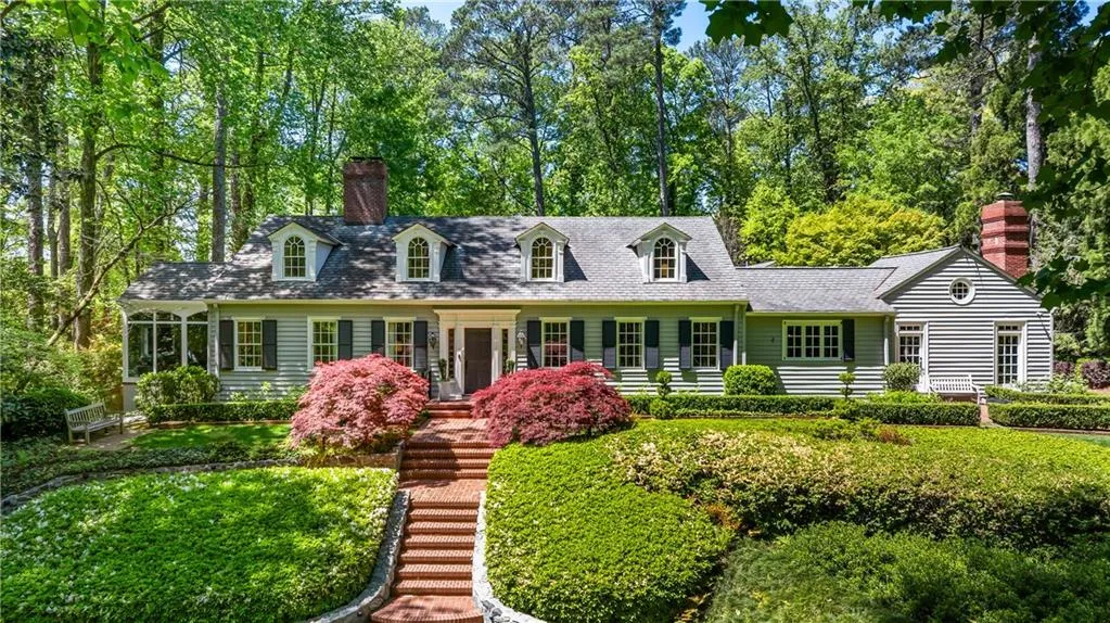 Cape cod home featuring a chimney and stairway