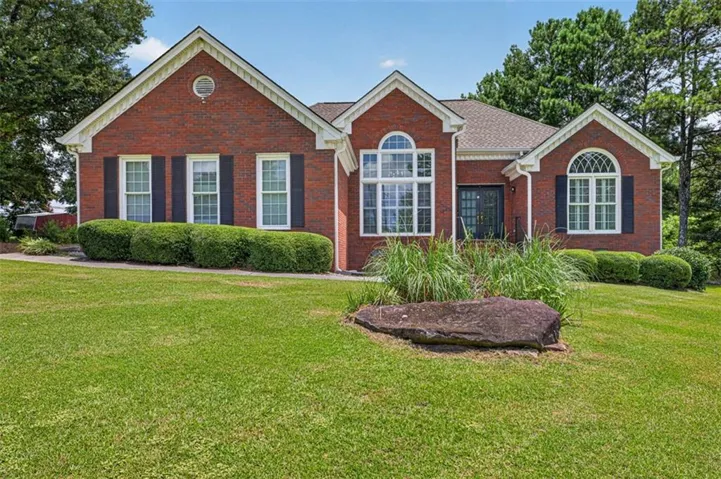 Brick facade residence with white trim, featuring a symmetrical window arrangement with dark shutters