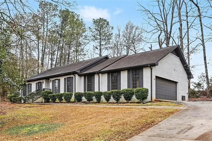 Single story home featuring driveway, brick siding, and a front lawn