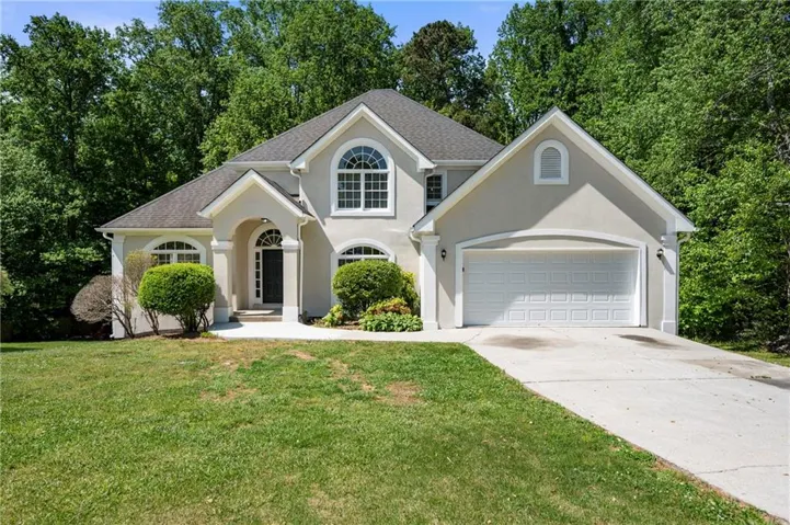Stucco exterior, arched entry, arched windows, attached garage, and pitched roof