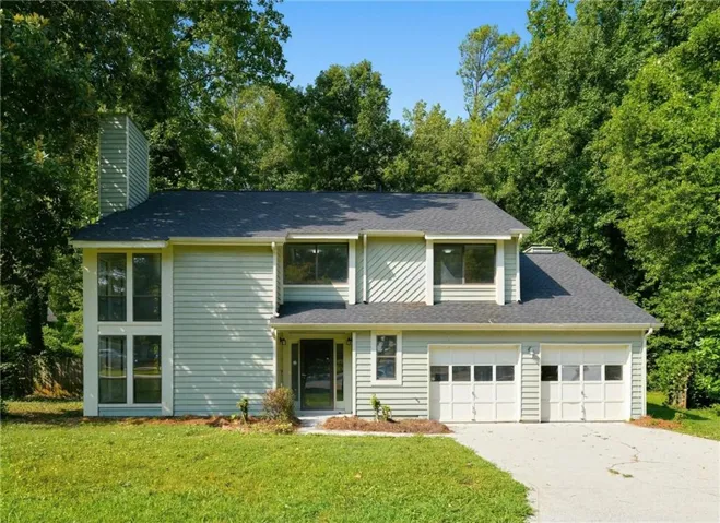 Two-story residence featuring light siding, a dark shingle roof, and a two-car garage