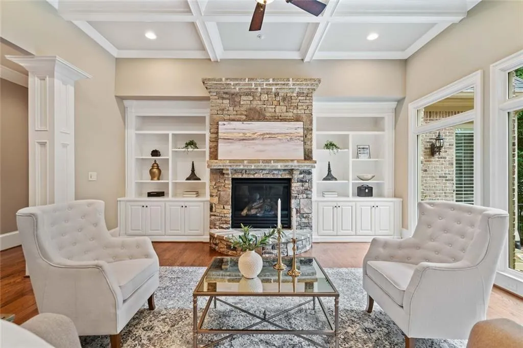 The cozy Family Room has a 12 ft coffered ceiling with recessed lighting, a stone gas fireplace with curved hearth and custom built-ins.